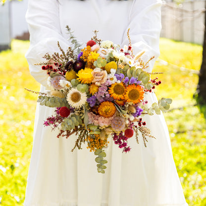 A hand-tied bouquet of real dried wildflowers with a mix of vibrant hues including yellow, red, lavender, blush, and berry tones.