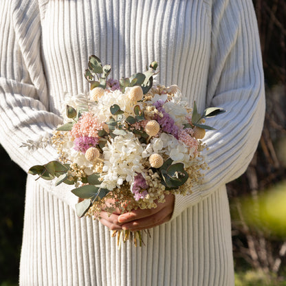 Person holding a bouquet of flowers in a natural setting